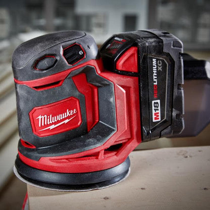 Milwaukee power sander on a wooden surface with blurred background